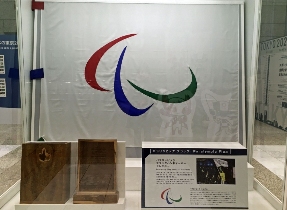 シンボル「スリーアギトス」が描かれたパラリンピックの旗。東京都庁第一本庁舎2階北側に設置されている「オリンピック・パラリンピックフラッグ展示コーナー」には、東京2020大会のPRを目的に、両大会の旗や過去大会の貴重な資料などが展示されている。入場無料／午前９時３０分～午後６時１５分／年末年始（12月29日～１月３日）や全庁閉庁日（一般開庁なし）などを除く。