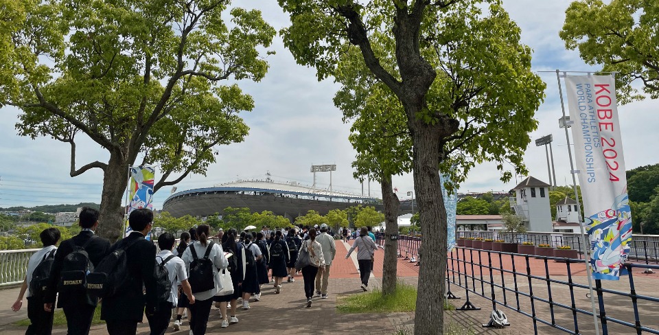 5月17日から25日まで神戸市で開かれたパラ陸上の世界最高峰の大会「KOBE2024世界パラ陸上競技選手権」。大会盛り上げの一環として実施された「学校観戦プログラム」によって兵庫県内から約3万人の児童・生徒が来場し、パラアスリートたちに勇気や力を与えた。写真は、最寄駅から会場のユニバー記念競技場に向かう道を急ぐ、ある日の生徒たちの姿