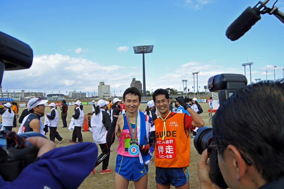 別府大分毎日マラソン視覚障害男子の部で2位に入った、全盲の和田伸也（左）と中田崇志ガイド。自身のもつ日本記録を約2分更新する2時間33分46秒でフィニッシュした和田を、多くのカメラと記者が取り囲んだ。（2016年2月7日／大分市営陸上競技場＝撮影：星野恭子）